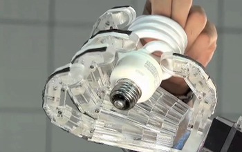 robotic hand and human hand holding a lightbulb